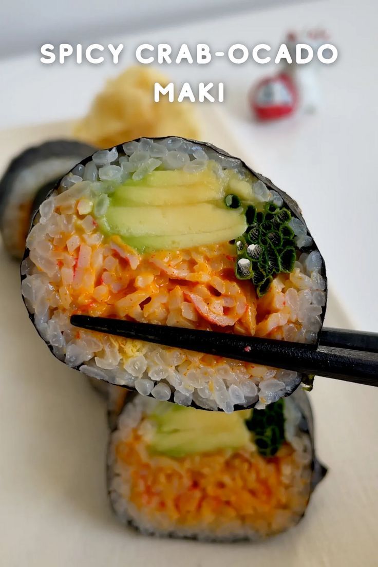 two sushi rolls with chopsticks on a white plate next to some vegetables