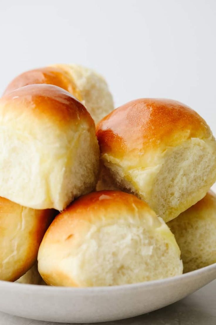 a white bowl filled with rolls on top of a table