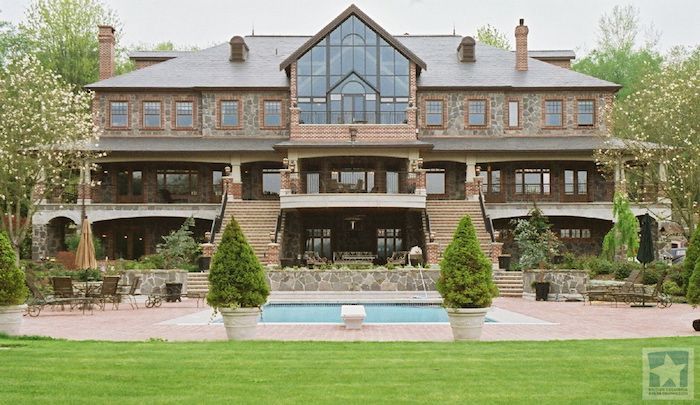 a large house with a pool in front of it and lots of greenery on the lawn