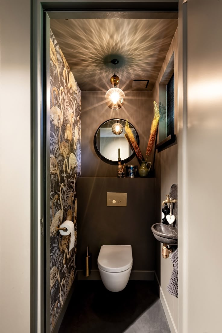 a bathroom with a white toilet sitting next to a sink under a round mirror on the wall