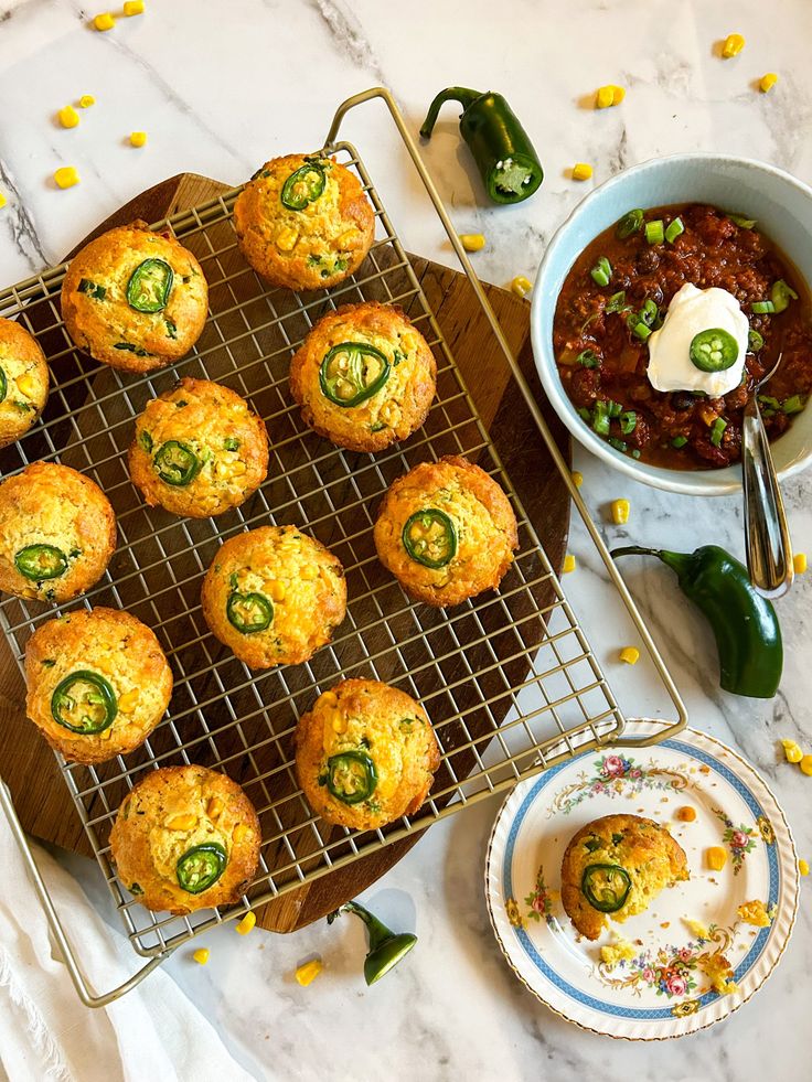 several muffins are cooling on a rack next to a bowl of chili