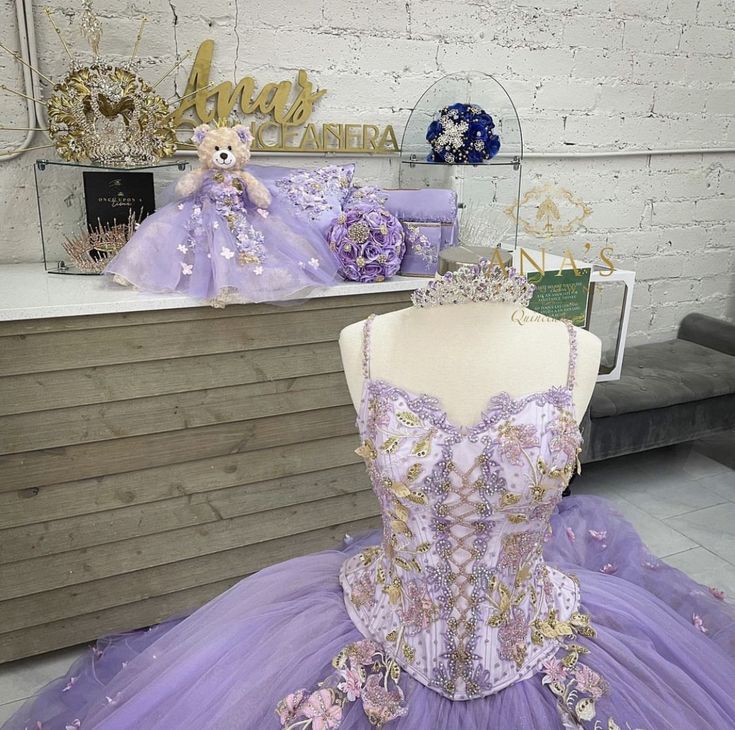 there is a purple dress on display in the store with gold and silver decorations behind it