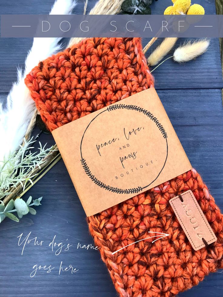 an orange crochet bag with a tag on it and some flowers in the background