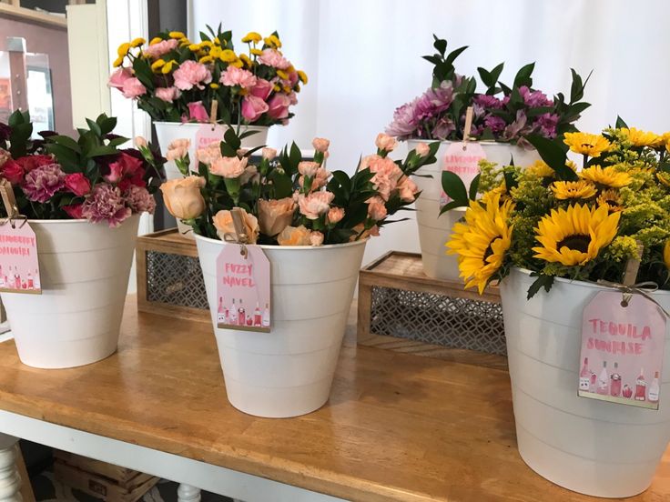 four buckets filled with flowers on top of a wooden table