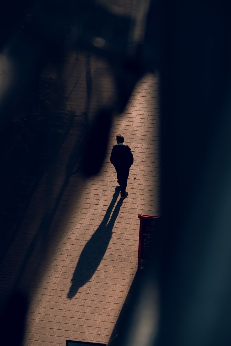 the shadow of a person walking down a sidewalk