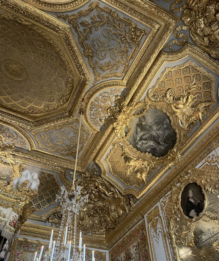 an ornate gold ceiling with chandeliers and paintings