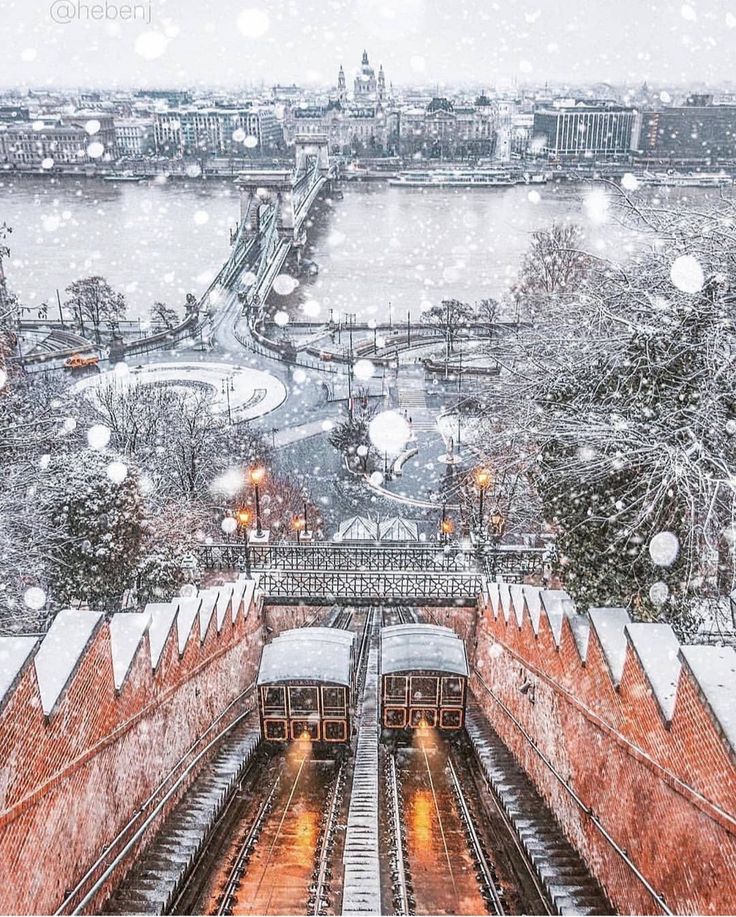 a train traveling down tracks next to a snow covered cityscape with lots of lights