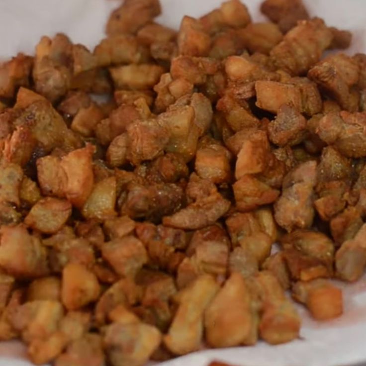 a pile of fried food sitting on top of a white paper bag filled with meat