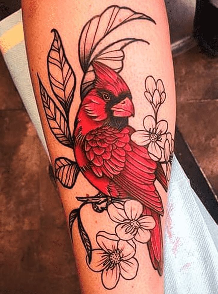 a red bird sitting on top of a tree branch with flowers in it's beak