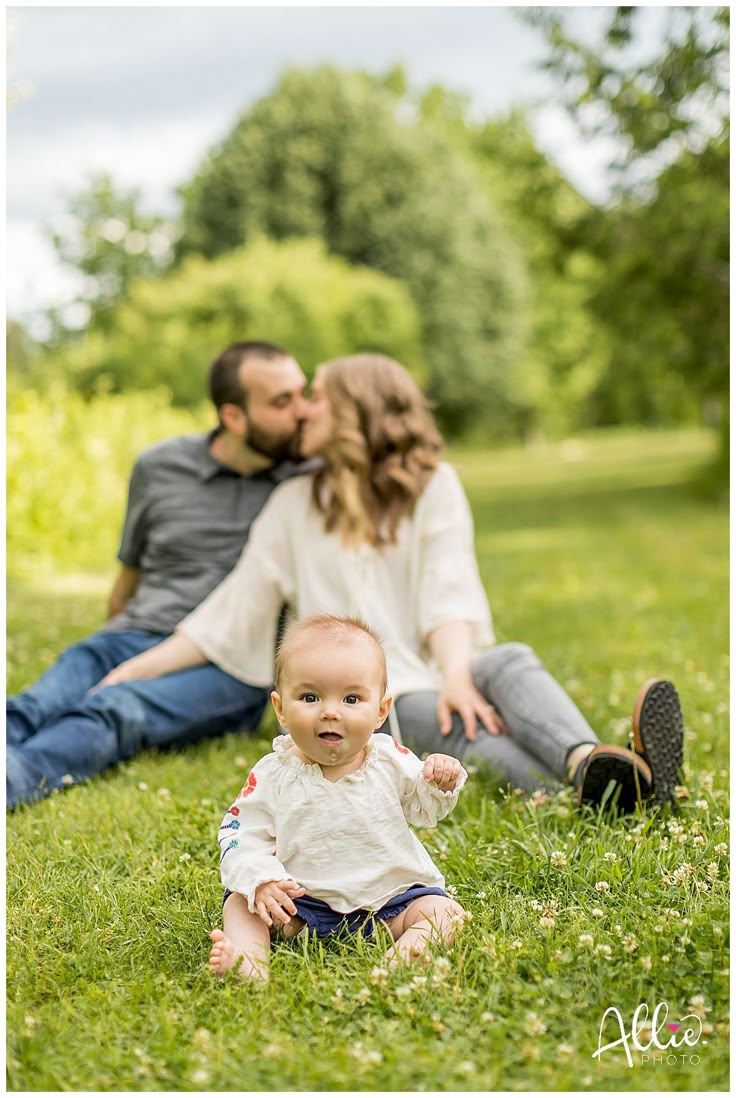 a baby sitting in the grass with his parents