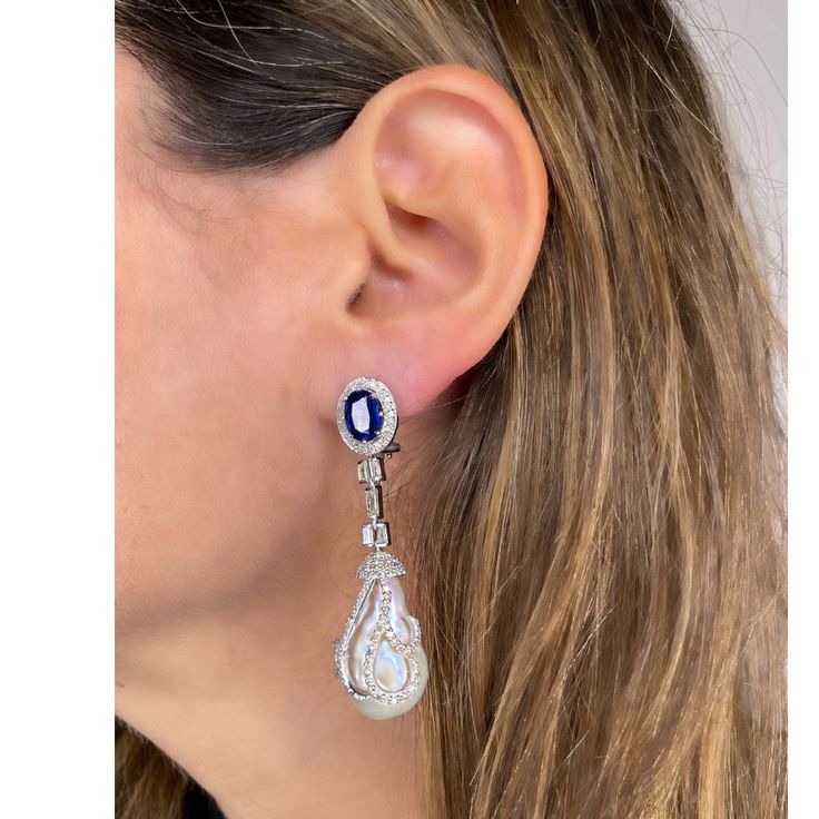 Delivery in 4-6 weeks Need it faster? Text us at (619) 247.5731 or Call us at (619) 365.4736 This pair of earrings are perfect for special occasions, this design gives the piece a feminine touch. Pearl, Kyanite & Diamonds Earrings Diamond: 1.77 ct Diamond Baguettes: 0.9 ct Pearl: 56.36 ct Kyanite: 4.65 ct Silver with Rhodium Plated weight: 8.3 grams Formal Bridal Gemstone Drop Earrings, Formal Bridal Drop Earrings With Gemstones, White Gold Gemstone Drop Diamond Earrings, Sapphire Earrings With Diamond Accents For Evening, Evening Earrings With Sapphire And Diamond Accents, Exquisite Sapphire Earrings In White Gold, Evening Sapphire Earrings With Diamond Accents, Sapphire Hallmarked Earrings For Wedding, Formal Sapphire Dangle Diamond Earrings