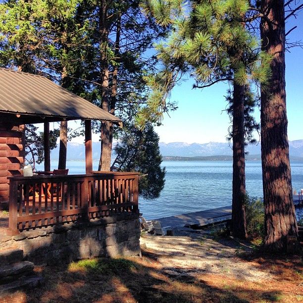 a cabin on the shore of a lake surrounded by trees