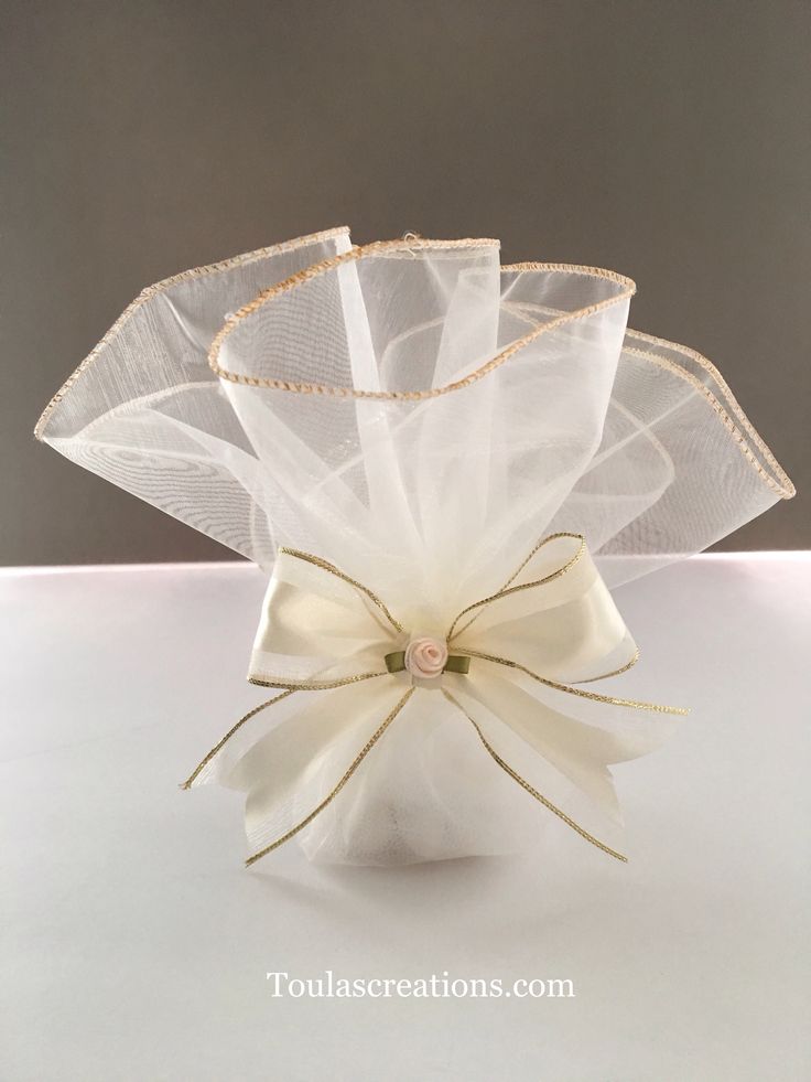 a white flower vase with a bow on the top and ribbon around it's edge