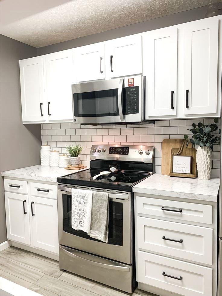 a kitchen with white cabinets and stainless steel appliances, including an oven, microwave, dishwasher, and coffee maker