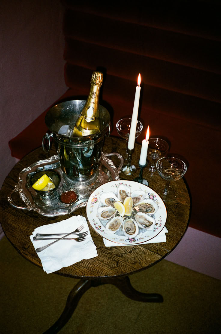 a table topped with plates and glasses next to a bottle of wine on top of a wooden table