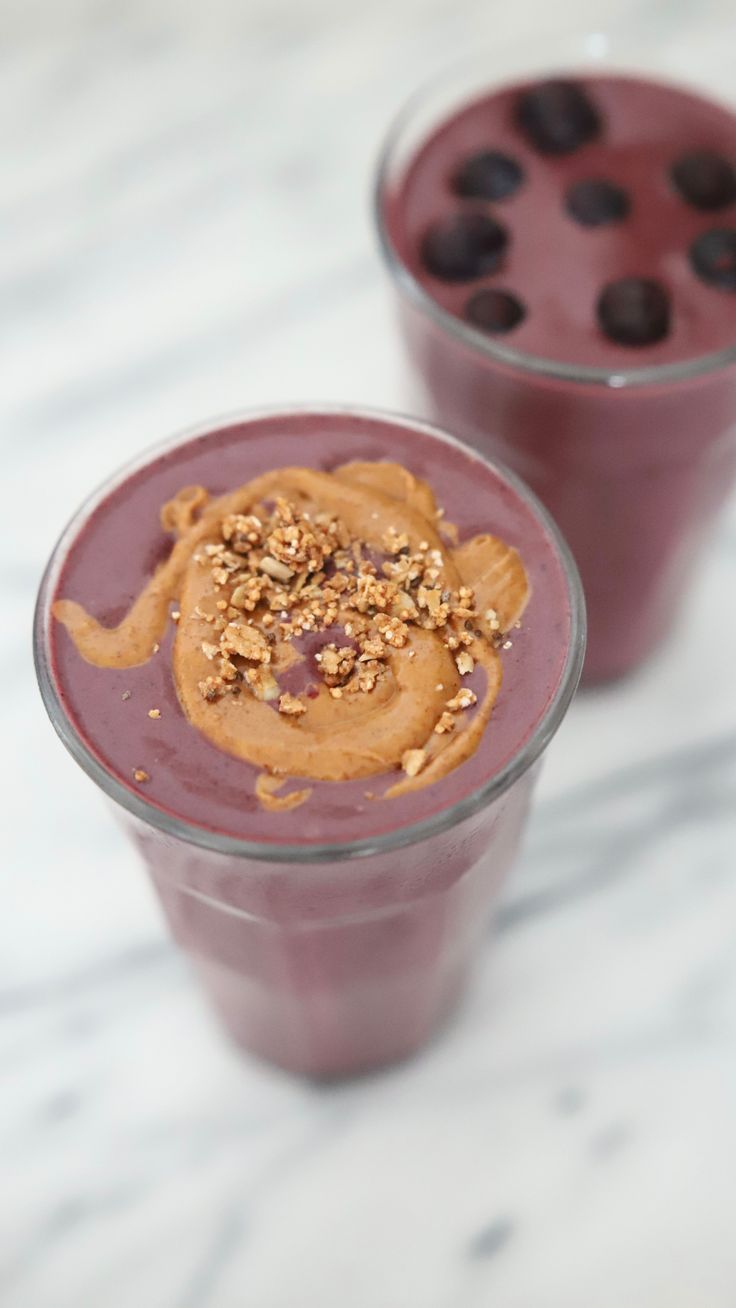 two glasses filled with smoothie and chocolate chips on the side, sitting on a marble surface