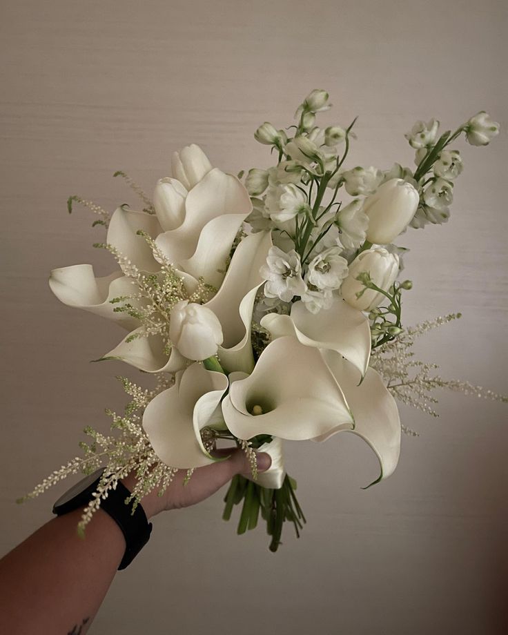 a hand holding a bouquet of white flowers