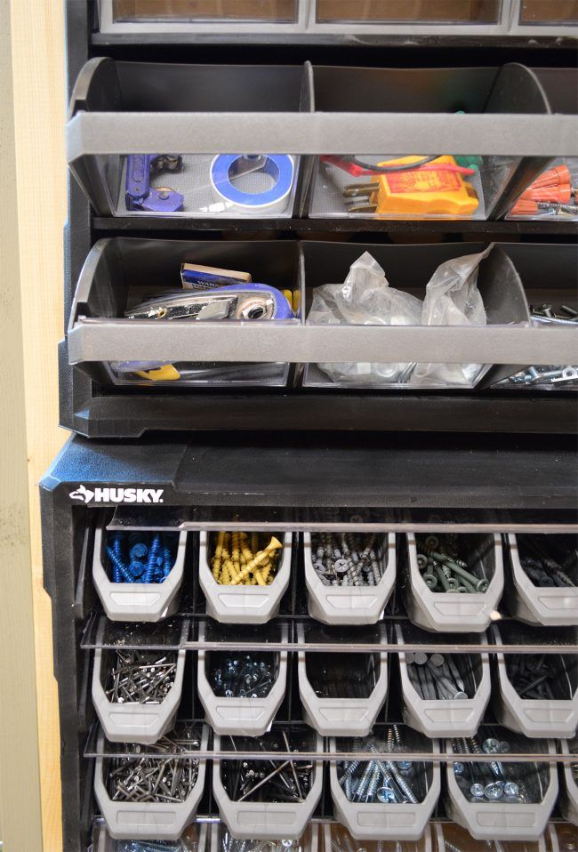 an organized shelf with plastic bins and various tools