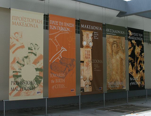 a row of posters on the side of a building in front of a wall with different designs