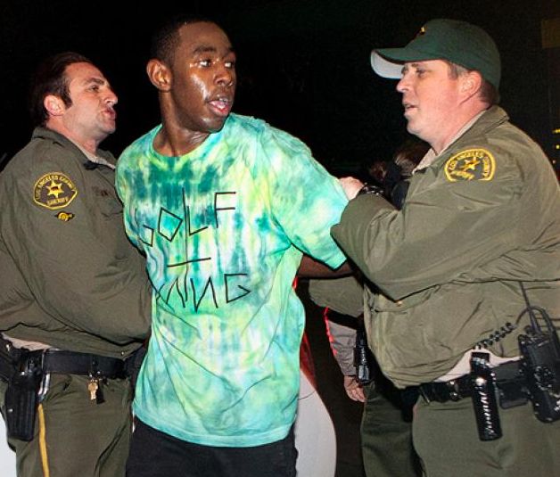 two police officers helping a man with his tie dye shirt