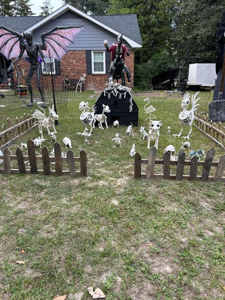 halloween yard decorations in front of a house with bats and skeletons on the lawn,