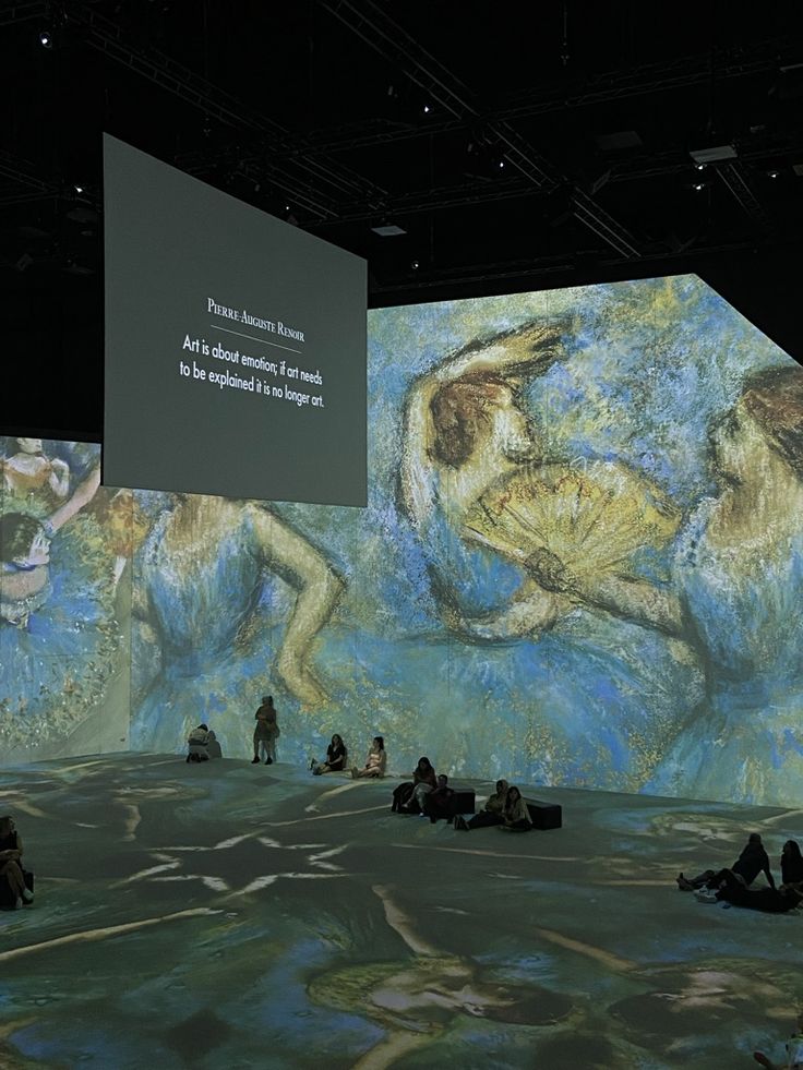 people are sitting on the ground in front of a large painting with words written on it