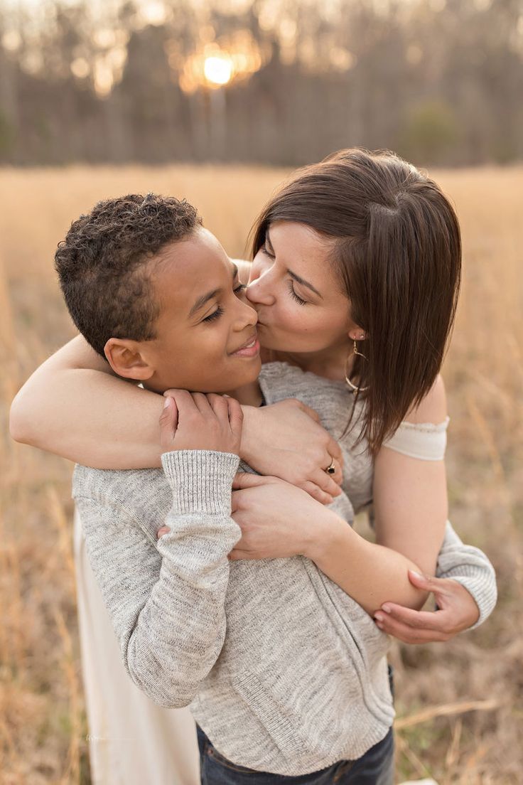 a young man and woman embracing each other in the middle of a field at sunset