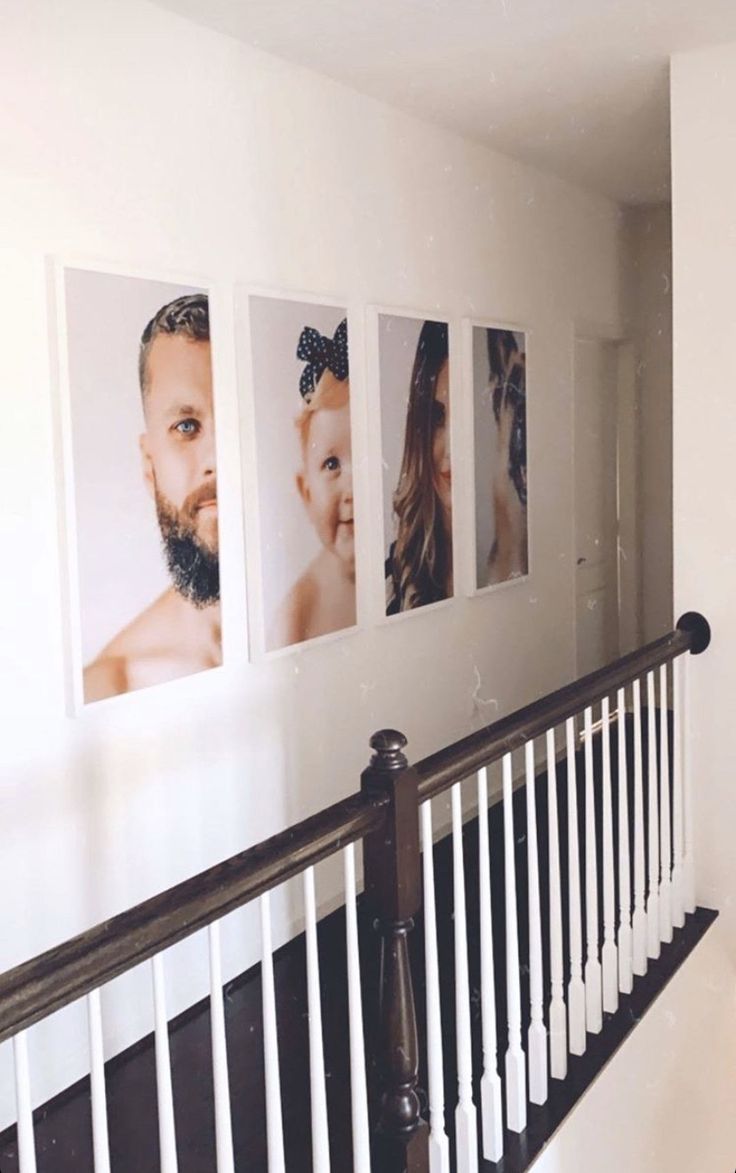 three pictures hang on the wall above a banister in a hallway with white railings