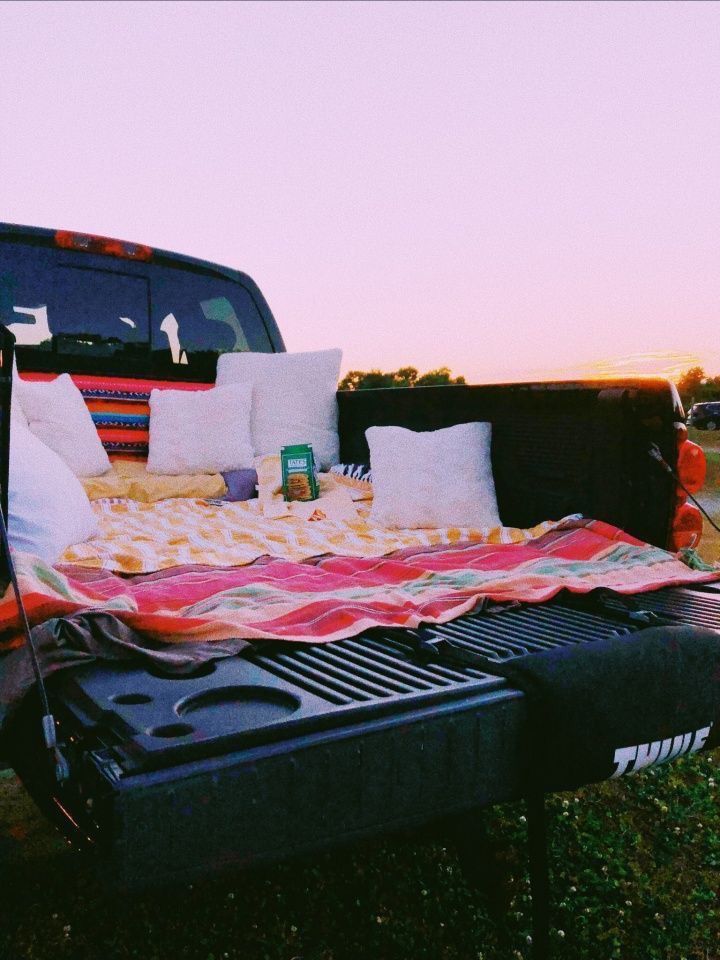 a bed sitting in the back of a truck with pillows on it's side