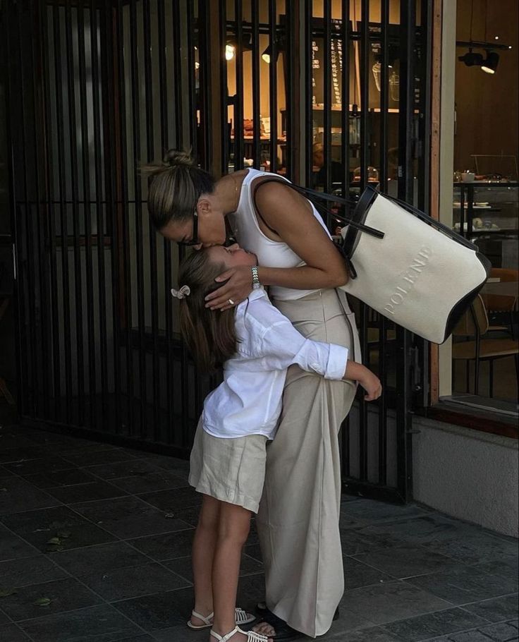 a woman is kissing a man on the cheek in front of an iron gate and building