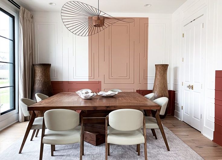 a dining room table with four chairs and a vase on the wall next to it