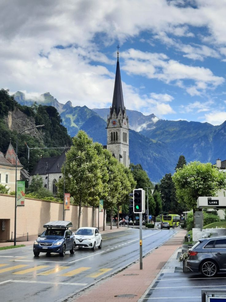 cars are driving down the street in front of a church