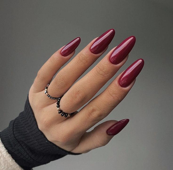 a woman's hand with red nail polish and black ring on it, holding onto her nails