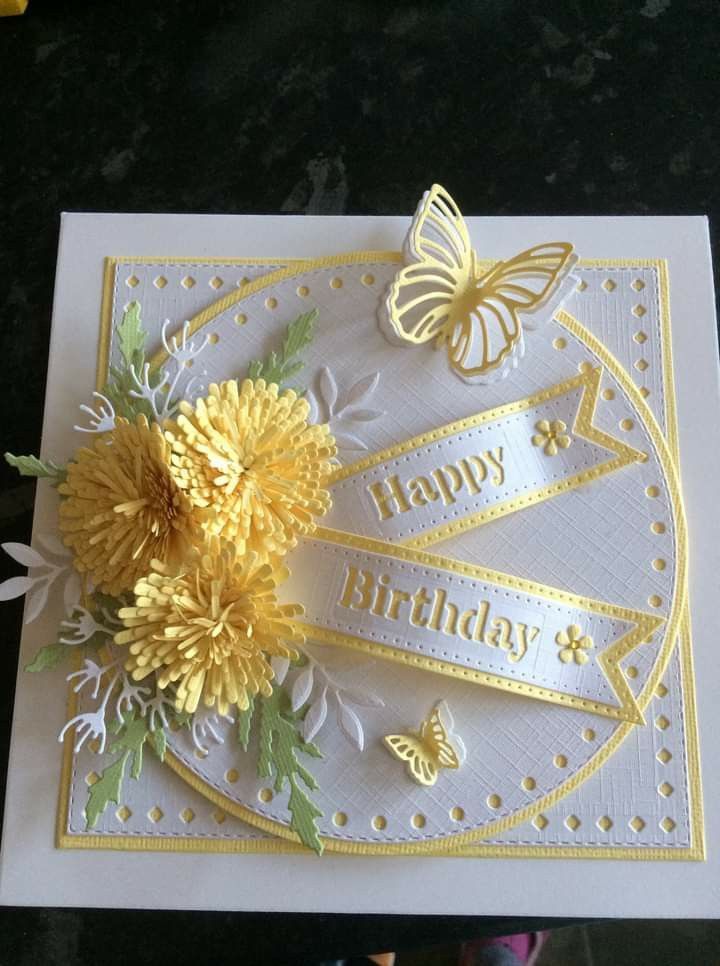 a birthday card with yellow flowers and butterflies on the front, sitting on a table