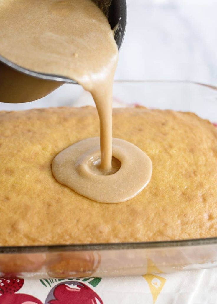 someone pouring peanut butter on top of a cake