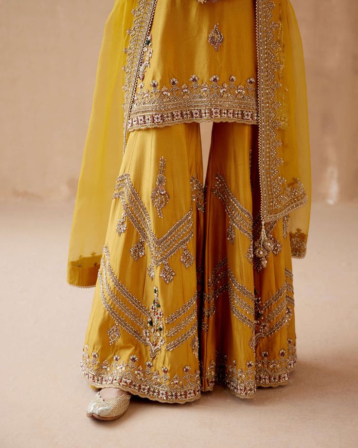 Editor's Note Introducing a stunning mustard kurta sharara adorned with intricate gold floral thread embroidery, elegantly highlighted with various embellishments. This captivating ensemble is ... Mustard Colour Combination, Sharara Suit Designs, Long Skirt Top Designs, Floral Thread Embroidery, Embroidery Kurta, Sharara Designs, Mom Daughter Outfits, Kurta Sharara Set, Haldi Outfit