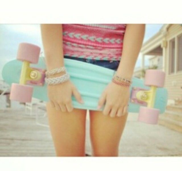 a girl with two bracelets on her arm and one holding a skateboard behind her back