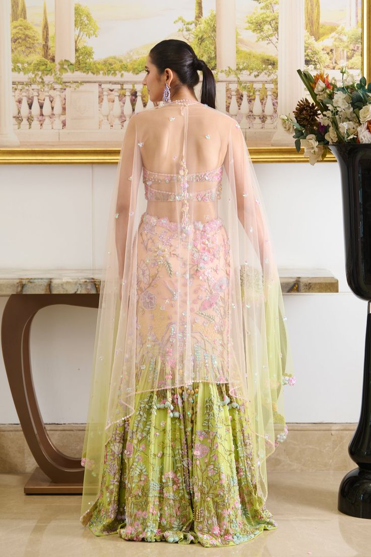 Introducing our Marina Lehenga Set, a mesmerizing Ombre blend adorned with botanical motifs, pastel-hued beads, crystal stones, moti, sequins, and seashell detailing. Paired with a glamorous halter-neck blouse adorned with fine hand embroidery and complemented by a translucent pre-stitched dupatta detailed with tiny sequined flowers. Halter neck blouse with tie-up straps attached with tassels at the back. The blouse contains a back center hook. The blouse embroidered with flower motifs comes with a cut-out detailing at the back. Mermaid-style floor-length skirt embellished with botanical embroidery accentuated with crystals, beads, and sea-shells detailing. Pretty tassel drop attached with strings on the left side of the skirt. Lehenga contains a metal zip on the left side. From Moledro’s Floor-length Embellished Multicolor Sharara, Floor-length Multicolor Embellished Sharara, Multicolor Embellished Floor-length Sharara, Pista Green Embellished Organza Sets, Wedding Lehenga Hand Embellished In Multicolor, Embellished Pista Green Wedding Gown, Embellished Multicolor Georgette Set, Bohemian Embellished Lehenga For Weddings, Bohemian Embellished Wedding Lehenga