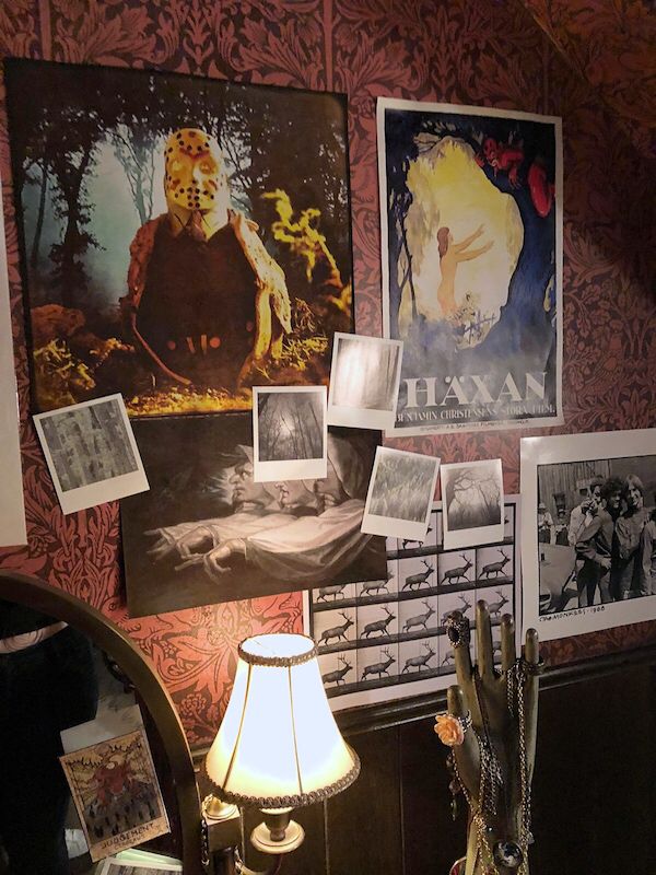 a room with many pictures hanging on the wall and a lamp next to it in front of a mirror