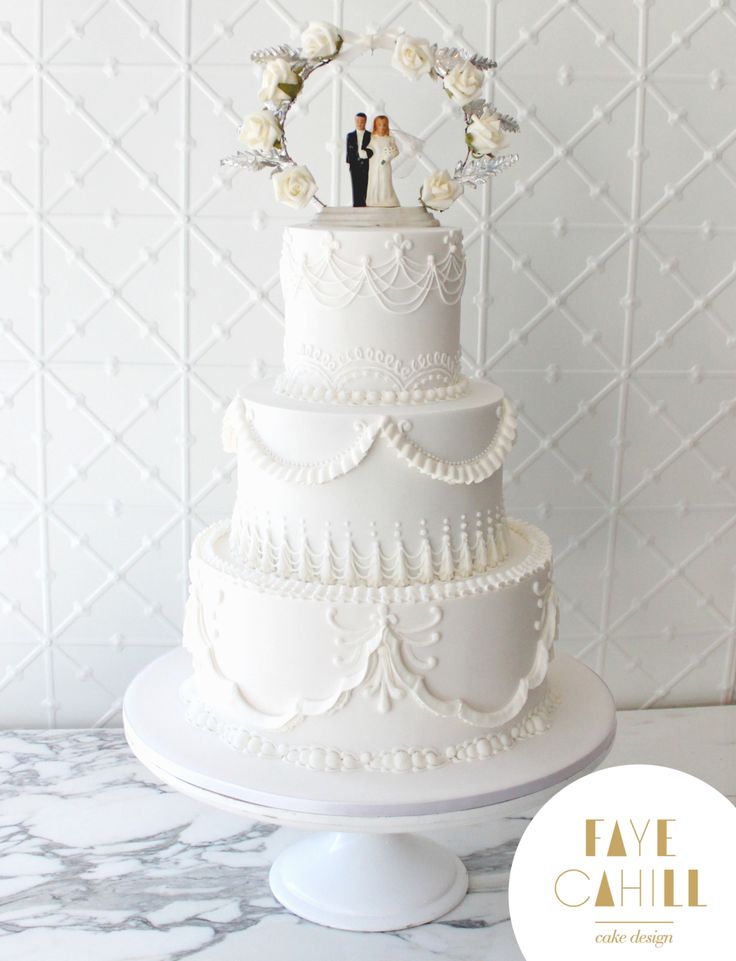 a white wedding cake with two people on top