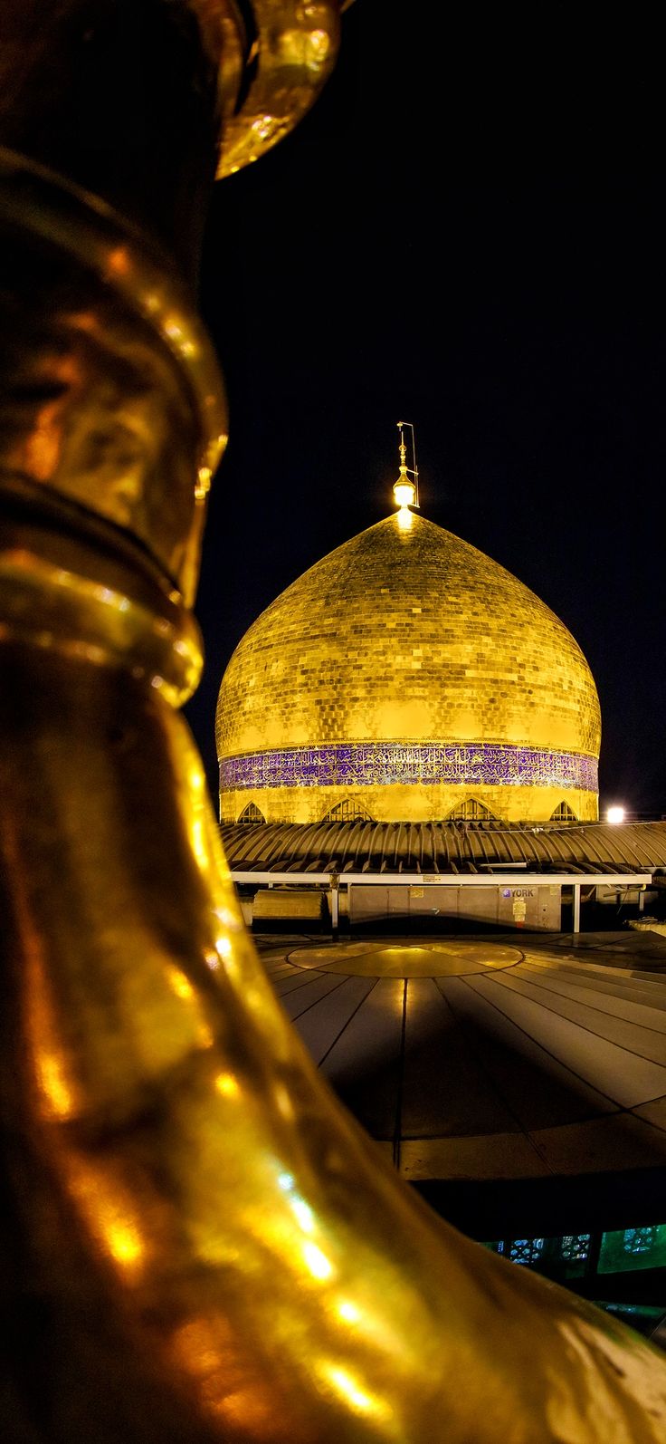 a golden statue is in front of a large building with a dome on it's side