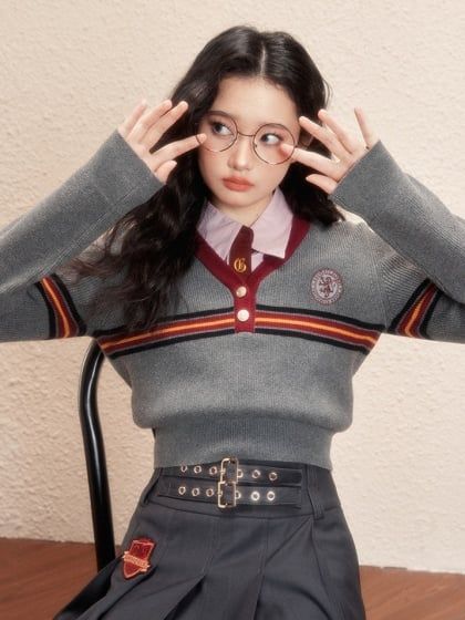 a young woman sitting in a chair holding her hands up to her head and wearing glasses