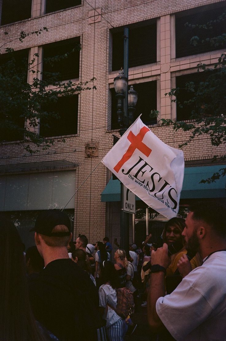 a group of people standing in front of a building with a sign that says jesus