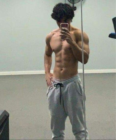 a shirtless man taking a selfie in front of a mirror with his cell phone