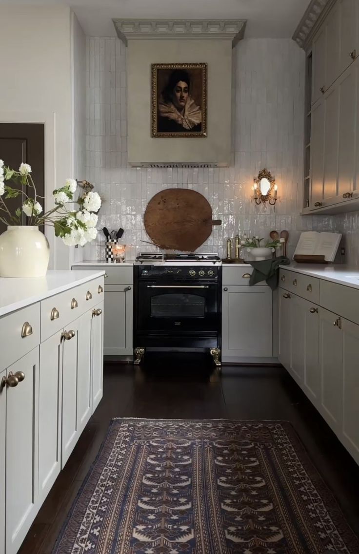 a kitchen with white cabinets and an area rug in front of the stove top oven