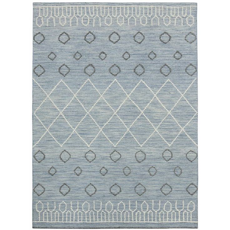 a blue and white rug with diamond shapes on the bottom, in front of a white background