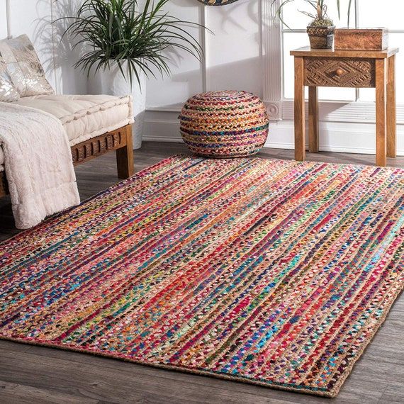 a multicolored rug in a living room next to a couch and table with potted plants