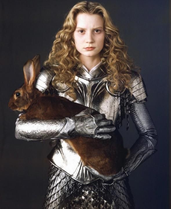 a woman dressed as a knight holding a rabbit in her arms and posing for the camera