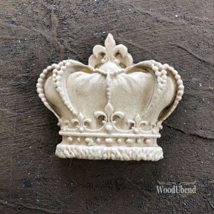 a white ceramic crown sitting on top of a wooden table next to a brick wall