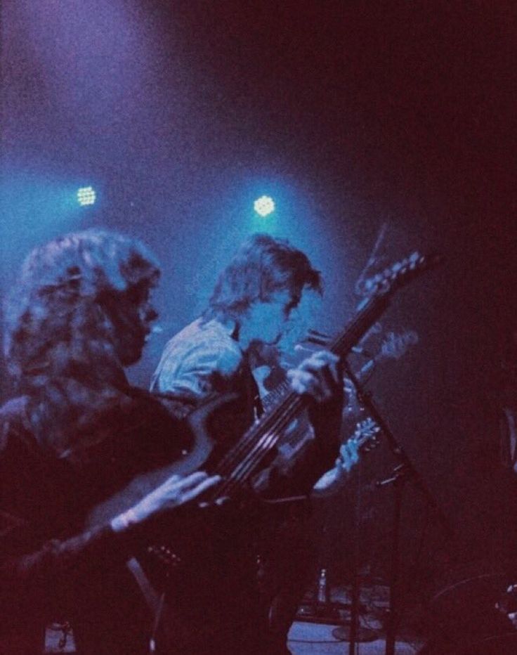 two people on stage playing instruments in the dark